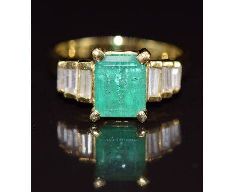 An 18k gold ring set with an emerald cut emerald of approximately 1.9ct and six baguette cut diamonds, 6.2g, size N