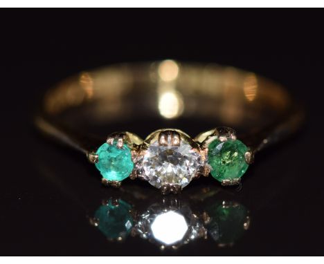 An 18k gold ring set with an old cut diamond of approximately 0.2ct and two emeralds, 1.8g, size N