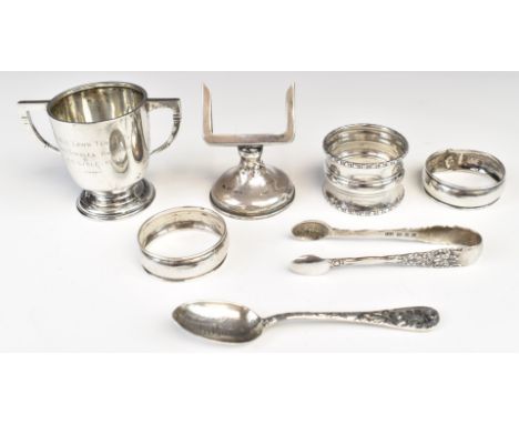 Hallmarked silver items comprising twin handled trophy cup, height 5.5cm, three various napkin rings, perpetual calendar base