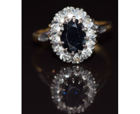 An 18ct gold ring set with an oval cut sapphire surrounded by diamonds, 5.2g, size P