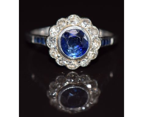 Art Deco platinum ring set with a round cut sapphire surrounded by diamonds, with further baguette cut sapphires to the shoul