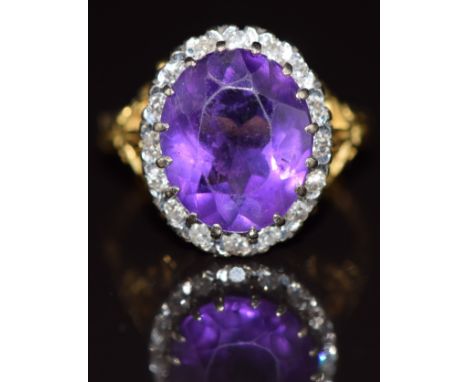 An 18ct gold ring set with an oval cut amethyst of approximately 4.1ct surrounded by diamonds, 6.4g, size M