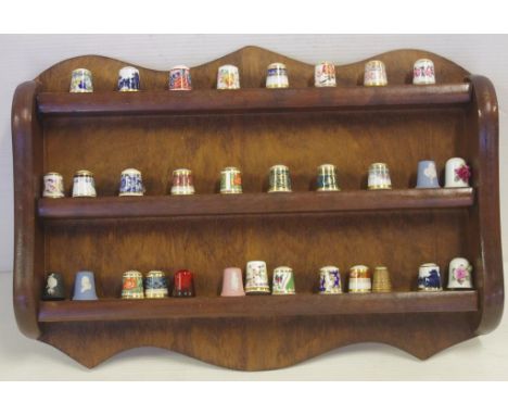Thirty one assorted ceramic thimbles to include Royal Doulton flambe, Wedgwood and Coalport, together with timber thimble wal