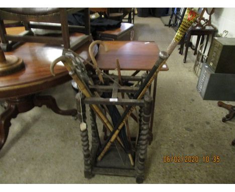 EARLY 20TH CENTURY OAK FRAMED BARLEY TWIST FOUR-SECTIONAL STICK STAND WITH A QUANTITY OF MIXED WALKING STICKS