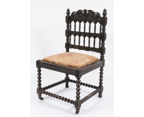 A 19th Century Indo Colonial carved ebonised side chair:, the spindle turned and arcaded back with shaped fret cut cresting d