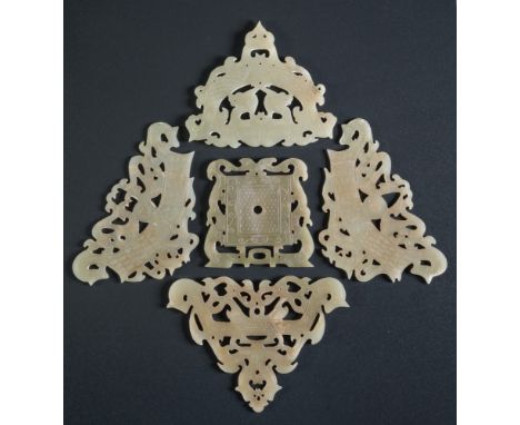A group of five Chinese celadon jade pendants: in archaic Warring States style, carved and reticulated with scaly dragons, ta