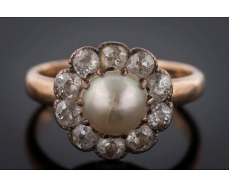 A gold, pearl and diamond circular cluster ring: with central button pearl 6.5mm diameter, claw-set within a surround of ten 