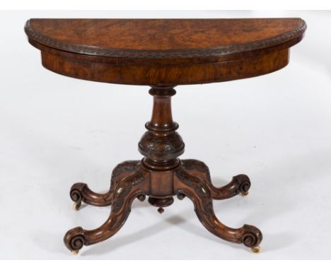 A Victorian carved and burr figured walnut half round card table:, the baize lined hinged top with a husk decorated border on