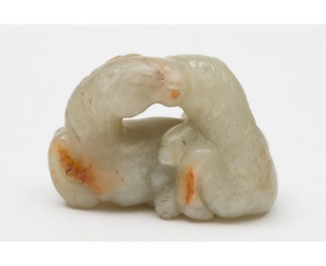 A Chinese jade carving of two reclining horses: with heads touching, one scratching it's neck with a hind leg, the stone of c