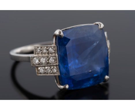 A platinum, sapphire and diamond ring: with central cushion shaped sapphire, 14.7mm x 13.5mm x 8.7mm deep between three-row d