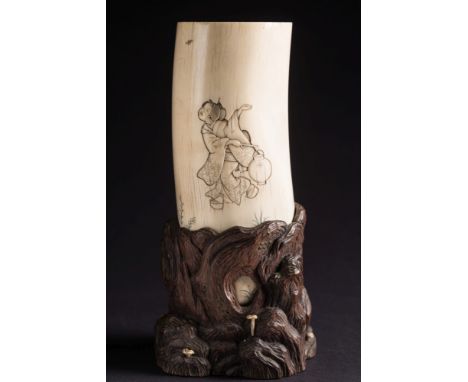 A Japanese carved ivory tusk vase: decorated with a courtesan and an attendant holding a lamp, signed, mounted in a naturalis