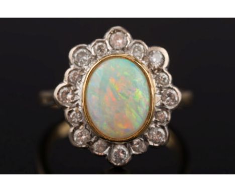 An 18ct gold, opal and diamond oval cluster ring: with central oval opal approximately 10mm long x 8mm wide in rub-over setti