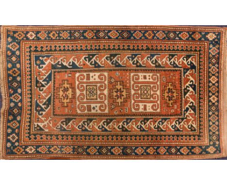 A Kurdish rug:, the brick red rectangular central panel with hooked and stepped stellar and oblong medallions, within a main 