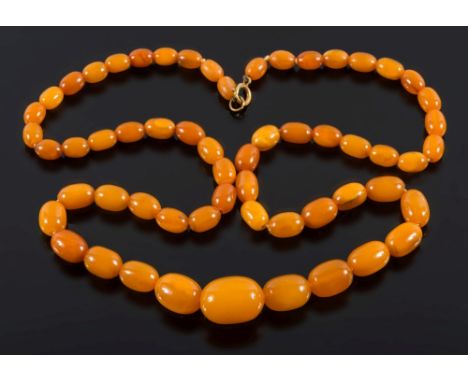 A graduated amber coloured bead, single string necklace: with 59 oblong beads graduated from 10mm to 24mm long and with bolt 
