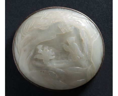 A Chinese jade oval plaque: carved with a figure paddling a boat within a lake landscape, the translucent stone of pale celad