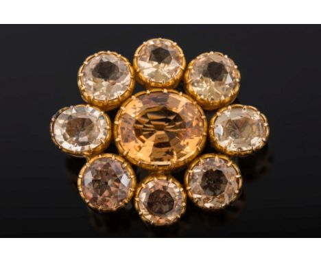 A late 19th century gold and topaz oval cluster brooch: with central oval topaz approximately 12mm x 10mm within a surround o