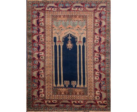 A Panderma rug:, the indigo architectural panel with a hanging lantern, enclosed by a main wine serated leaf and geometric me