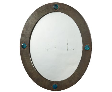 Liberty & Co, a brass wall mirror: the oval mirror plate enclosed by a brass frame with Ruskin ceramic roundels, the ivorine 
