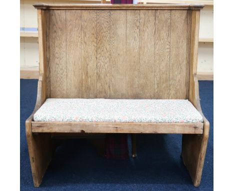 An early 20th century pitch pine hall settle with corniced flat back over plain seat with loose cushion, 113cm high x 107cm w