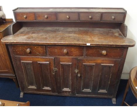 An early 20th century stained pine kitchen dresser with five drawer superstructure over unit with three drawers over three pa