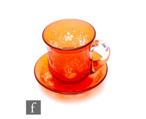 A Webbs of Stourbridge flashed glass tea cup and saucer, peach red over clear, intaglio cut trailing flowering branches, heig