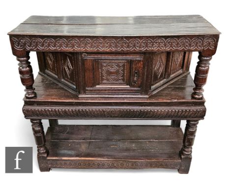 A 17th Century and later constructed two tier oak buffet, the moulded edge plank top above an angled livery cupboard below a 