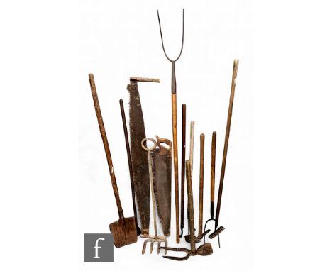 A collection of 19th and early 20th Century agricultural and farm tools, to include a band saw, hand saw, malt shovel, pitch 