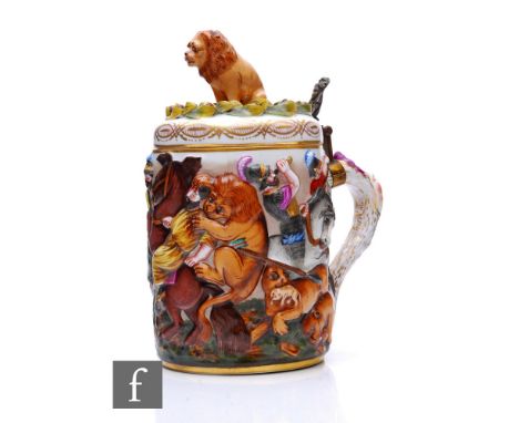 A late 19th Century Capodimonte porcelain lidded stein, relief moulded in the round with lion hunting scene, the hinged cover