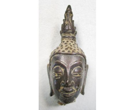 A Thai bronze head of the Buddha, his serene face flanked by long lobed ears, his curled hair surmounted by spire shaped flam