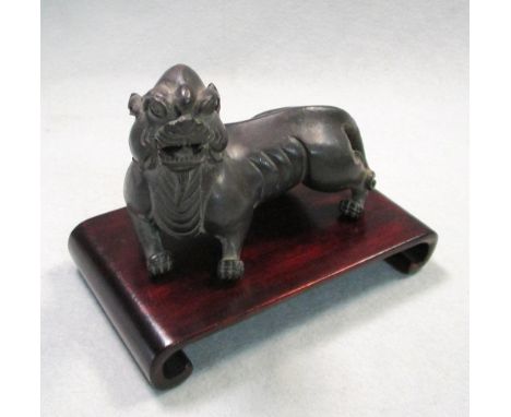A 19th century bronze tiger and wood stand, the beast snarling as it walks with its head raised over its left shoulder, 11cm 