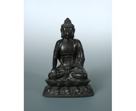 An 18th/19th century bronze Buddha seated cross legged on a double lotus throne, his right hand resting on his right knee tow