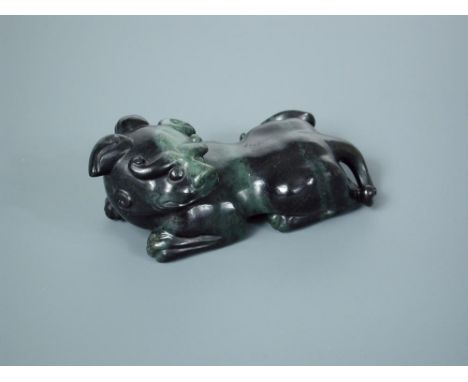 A dark spinach green jade qilin, the single horned beast with its head turned over its left shouder, 12cm (4.75 in) wide  