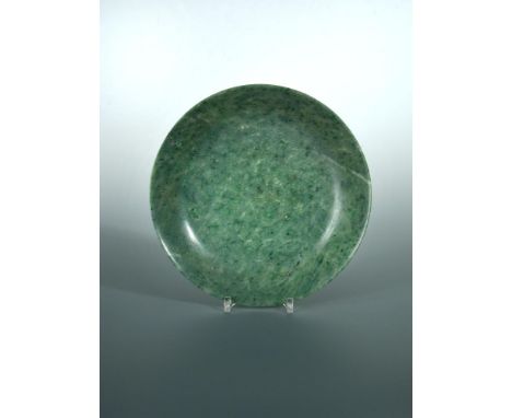 A spinach green jade deep dish, the mottled green stone with a speckling of black inclusions, 24cm (9.75 in) diameter  