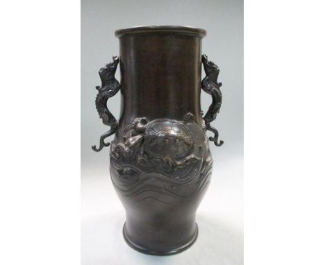 A late 19th/early 20th century bronze vase, the swollen cylindrical shape applied with dragon handles, their tails on a relie