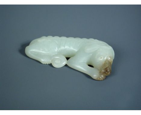 A nephrite jade sleeping dog pendant, the pale green hound with a grey muzzle, its collar tied with a bell, 6.5cm (2.5 in) wi