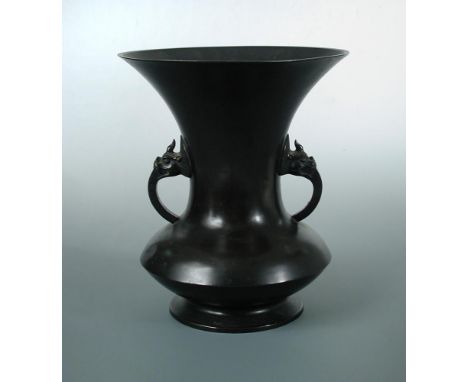A late 19th/early 20th century bronze vase, the tall trumpet shaped neck above a disc shaped and flat foot rim, the handles o