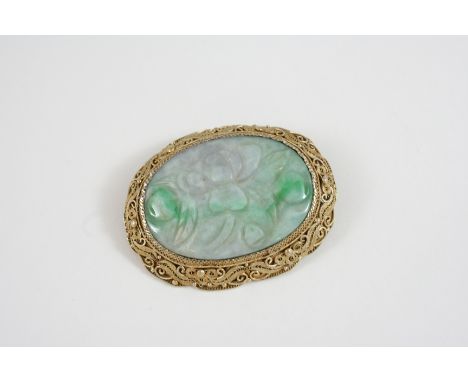 A CARVED JADE BROOCH the oval section of jade is set in an ornate silver gilt mount, 5.5cm. wide. 