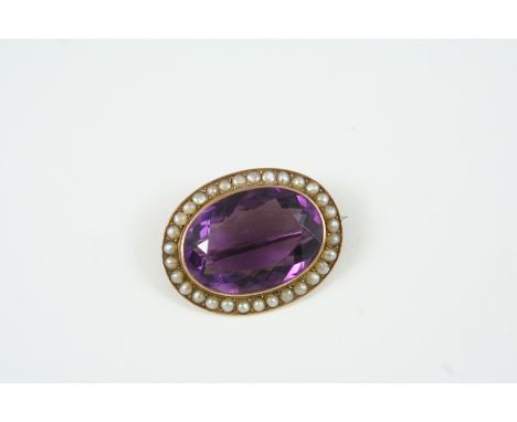 AN AMETHYST AND PEARL BROOCH the oval-shaped amethyst is set within a surround of half pearls, in 9ct. gold, 3.75cm. wide. 