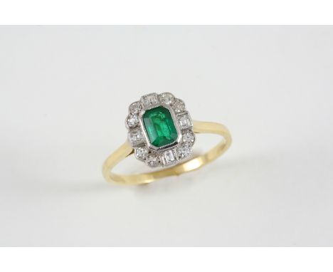 AN EMERALD AND DIAMOND CLUSTER RING the rectangular-shaped emerald is set within a surround of square-cut and circular-cut di