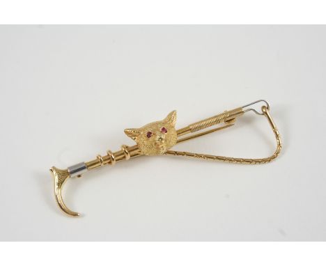 A 9CT. GOLD HUNTING STOCK PIN formed as a whip centred with a fox mask, with ruby eyes, 6.5cm. long. 