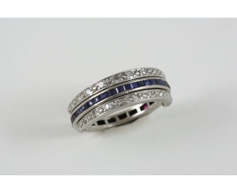 A RUBY, SAPPHIRE AND DIAMOND SWIVEL ETERNITY RING set to one side with calibre-cut rubies, to the other side with calibre-cut