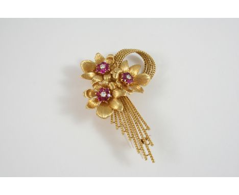 AN 18CT. GOLD, RUBY AND DIAMOND BROOCH BY KUTCHINSKY formed as a spray of three flowerheads, each centred with a circular-cut