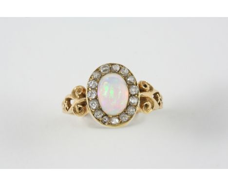 AN OPAL AND DIAMOND CLUSTER RING the oval solid white opal is set within a surround of rose-cut diamonds, in gold. Size S. 