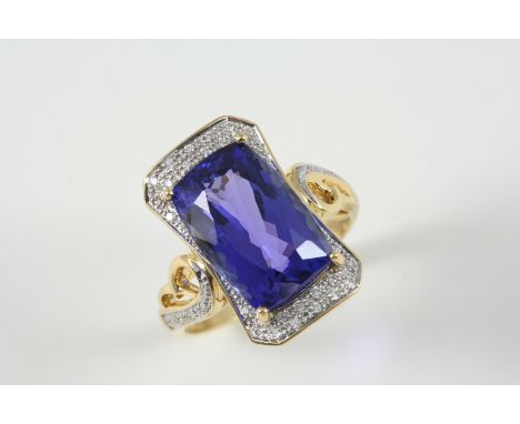 A TANZANITE AND DIAMOND RING the rounded rectangular-shaped tanzanite is set within a surround of small diamonds, with furthe