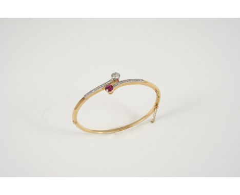 AN EARLY 20TH CENTURY RUBY AND DIAMOND HALF HINGED BANGLE the cross-over design is set with an old brilliant-cut diamond and 