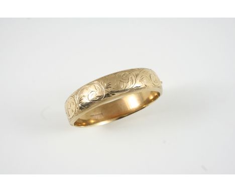 A 9CT. GOLD HALF HINGED BANGLE with engraved floral decoration to one side, 23 grams. 