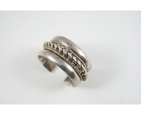 AN EGYPTIAN  SILVER BANGLE centred with a twisted silver design within a rope border, 142 grams. 