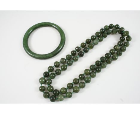 A SINGLE ROW UNIFORM JADE BEAD NECKLACE 77cm. long, together with a jade bangle. 