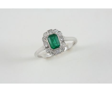 AN EMERALD AND DIAMOND CLUSTER RING the octagonal-shaped emerald is set within a surround of four square-shaped and eight cir