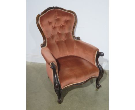 A 19th century carved walnut button back armchair on shaped legs